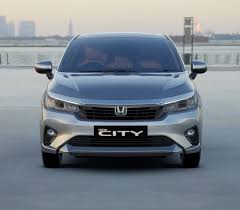 Honda Cars India has confirmed the City facelift will launch on May 22 2026 alongside the ZR-V hybrid SUV. This is the second update to the fifth generation City which has been on sale since 2020. With the next generation City not arriving until 2028 this facelift plays a crucial role in keeping India's most trusted sedan competitive against the Hyundai Verna Skoda Slavia and Volkswagen Virtus. Here is everything confirmed and expected about the 2026 Honda City facelift. Why This Facelift Matters The current Honda City has fallen slightly behind rivals on features. The Hyundai Verna offers ventilated seats 7 airbags a digital cockpit and more comprehensive ADAS. The Skoda Slavia and Volkswagen Virtus offer better build quality and driving dynamics. The 2026 facelift addresses these gaps directly by adding features that City buyers have been requesting while retaining everything that makes the City special — its legendary reliability spacious cabin and smooth refined driving experience. Design Changes — Leaked Images Confirm Leaked images ahead of the May 22 launch confirm the 2026 City facelift gets a heavily revised front fascia. The redesigned grille with honeycomb mesh revised LED headlamps with integrated DRLs new bumper with angular inserts and Honda's new signature H logo on the bonnet give it a noticeably fresher look. The rear gets redesigned tail lamps and updated bumper styling. New alloy wheel designs on higher variants complete the exterior refresh. The side profile remains largely unchanged — the City's clean proportions needed no significant alteration. Key Feature Additions The 2026 City facelift is expected to add several meaningful features that address its main shortcomings versus rivals. A larger 10.25 inch touchscreen replaces the current 8 inch unit — a much needed upgrade that brings it in line with newer rivals. A fully digital instrument cluster replaces the semi digital unit giving the cabin a more modern premium feel. Ventilated front seats are expected as a segment essential addition for Indian summers. A 360 degree surround view camera is expected on higher variants — borrowing hardware from the Elevate. An electrically adjustable driver's seat on top variants is another expected premium addition. Honda Sensing ADAS The updated Honda Sensing Level 2 ADAS continues with smoother calibration specifically for Indian traffic conditions. Adaptive cruise control lane keep assist automatic emergency braking with improved pedestrian detection and collision mitigation braking system are the key features. Honda's ADAS calibration has always been praised for real world usability in Indian conditions — a genuine advantage over some rivals whose ADAS can feel intrusive or unreliable on Indian roads. Engine — Proven and Unchanged The 2026 City facelift retains its two proven powertrain options. The 1.5 litre i VTEC naturally aspirated petrol produces 121bhp and 145Nm paired with a 6 speed manual or CVT automatic. This engine's refinement and smoothness remain class leading — the 4 cylinder unit runs with a sophistication that 3 cylinder rivals cannot match. The 1.5 litre e HEV strong hybrid producing 126bhp combined with the e CVT continues as India's most fuel efficient sedan delivering over 26 kmpl in city conditions. For high mileage urban buyers the hybrid remains the most financially compelling sedan choice in India. Expected Price The 2026 Honda City facelift is expected to be priced with a modest increase over the current range which starts at ₹12.07 lakh and tops out at ₹16.07 lakh for petrol variants and ₹20 lakh for the hybrid. Expect the facelift to start at approximately ₹12.50 lakh with the hybrid topping out around ₹20.50 to ₹21 lakh. City vs Rivals After Facelift Against the Hyundai Verna the updated City will close the feature gap significantly. The Verna still wins on outright feature count and the turbo petrol's performance but the City's reliability advantage and hybrid efficiency make it the stronger long term financial choice. Against the Skoda Slavia and Volkswagen Virtus the City wins on reliability and hybrid efficiency while the German duo win on build quality and driving dynamics. Against the Maruti Dzire the City wins on refinement space and features while the Dzire wins on price fuel efficiency in the petrol variants and Maruti's service network. Who Should Wait For The Facelift If you are currently considering buying a Honda City waiting until May 22 for the facelift makes complete sense. You will get the new design ventilated seats larger touchscreen and 360 degree camera at a similar price to the current model. There is no reason to buy the current pre facelift City when the update is just 10 days away. Verdict The 2026 Honda City facelift comes at exactly the right time. By adding the features that buyers had been requesting while retaining the City's core strengths of refinement reliability and hybrid efficiency Honda has ensured its most important product remains competitive through to the next generation model in 2028. Watch motormogul.in for our complete review with final prices on May 22 when the 2026 City facelift officially launches in India.